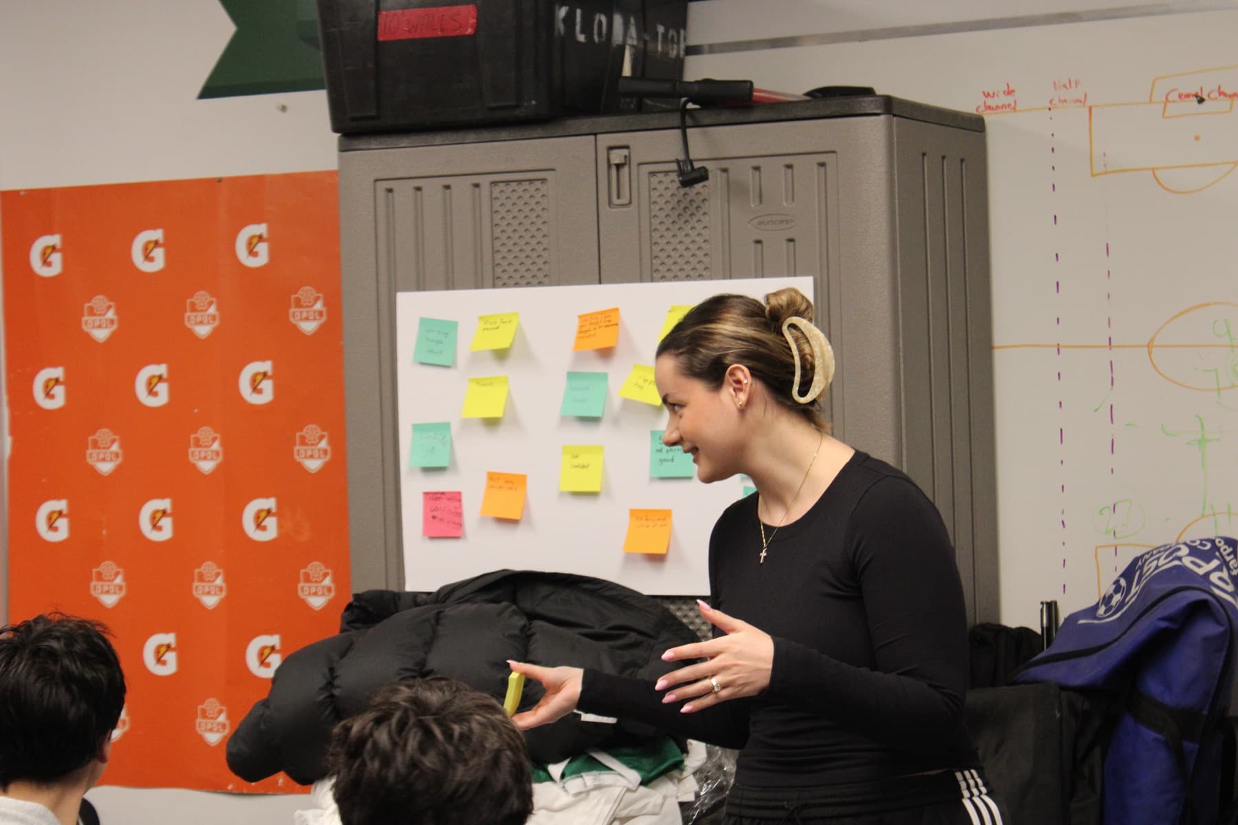 Amalia facilitating a workshop activity in front of a board of athletes' notes